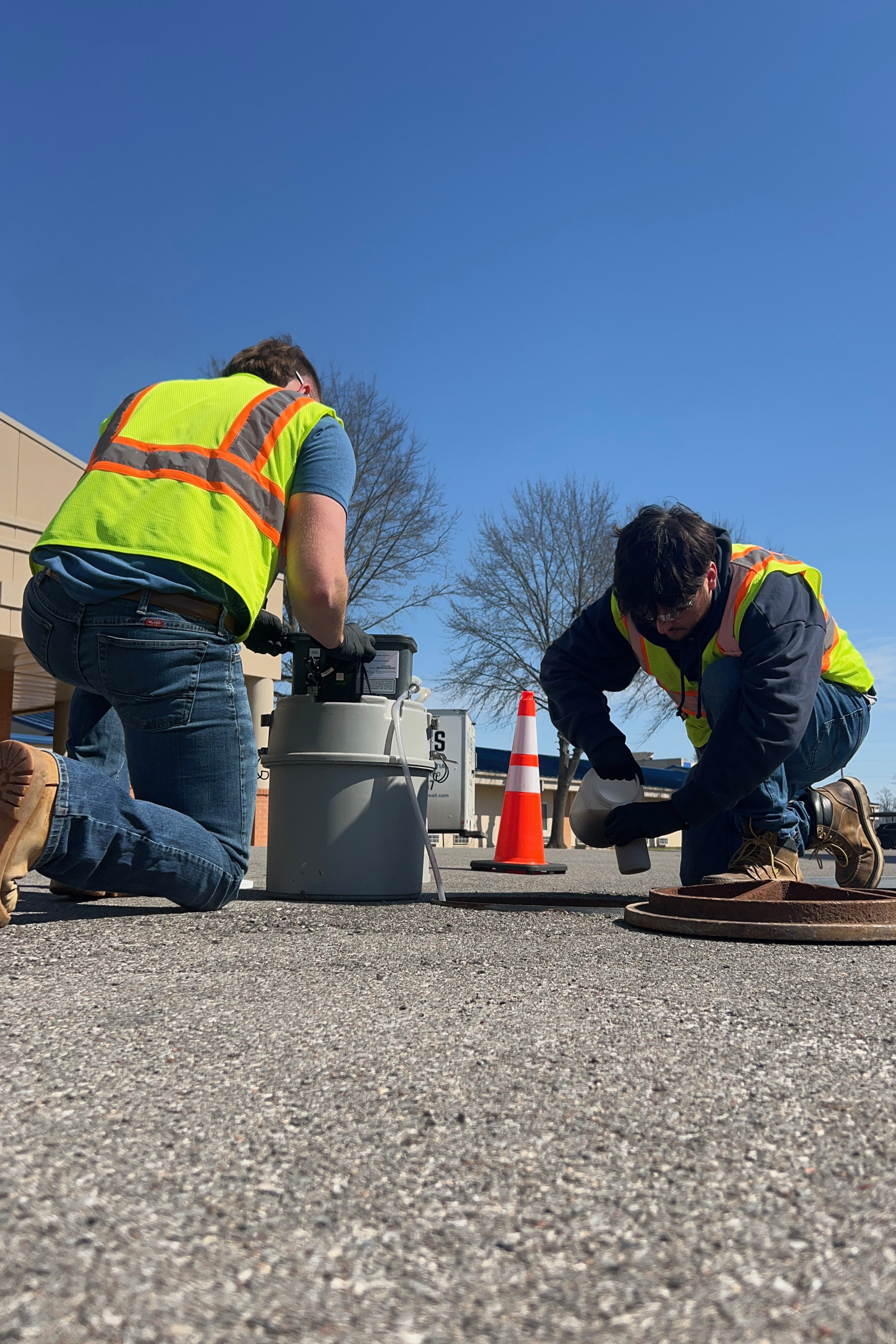 Two HydroPoint field technicians collecting a sample near a manhole.